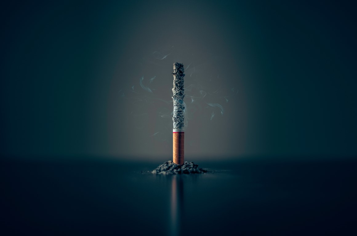 Image of a cigarette, on it's end, burnt through with the ash stacked up